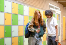 Zwei Jugendliche stehen in einer Schule vor einem Schließfach. Foto: IMAGO / Image Source