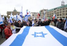 Teilnehmer einer proisraelischen Demonstration am 6. Oktober halten gemeinsam eine große israelische Flagge.