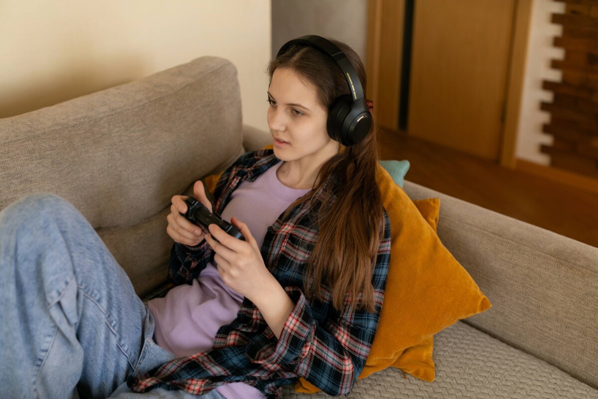 Weibliche Spielerin, die abends auf einem Sofa in einem gemütlichen Wohnzimmer Videospiele genießt. Bild: IMAGO/Zoonar Weibliche Spielerin, die abends auf einem Sofa in einem gemütlichen Wohnzimmer Videospiele genießt. Bild: IMAGO/Zoonar