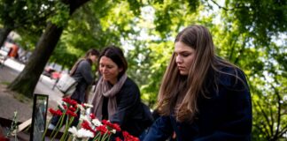Menschen legen bei der Gedenkveranstaltung zu Çetin Merts Tod vor 50 Jahren Blumen vor die Gedenktafel.