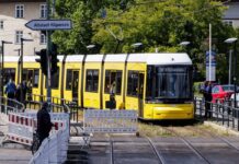 Eine Straßenbahn fährt in den gesicherten Bereich an der gesperrten Brücke an der Wuhlheide im Ortsteil Oberschöneweide. 