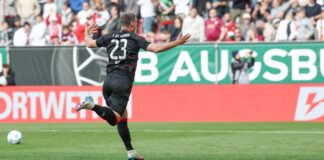 Berlins Matchwinner Andrej Ilic läuft nach seinem Siegtor jubelnd vor den Union-Fanblock. Augsburgs Torwart Finn Fahmen liegt geschlagen am Boden.