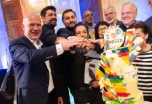 Die Regenbogentorte serviert die Initiative Maneo jedes Jahr im Mai. Kai Wegner (CDU, links) hat sie dieses Mal angeschnitten.