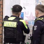 Zwei Polizisten entfernen ein Plakat, das den am Mittwoch erschossenen Deutsch-Israeli Yaron Lischinsky zeigt.