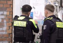 Zwei Polizisten entfernen ein Plakat, das den am Mittwoch erschossenen Deutsch-Israeli Yaron Lischinsky zeigt.