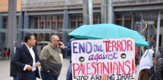 Eine Demonstrantin hält bei einer Propalästinensischen Demonstration auf dem Potsdamer Platz ein Schild hoch.