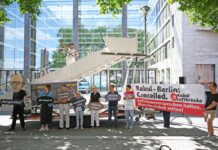 Aktivsten stehen während einer symbolischen Protestaktion am Weltflüchtlingstag zur Unterstützung mehrerer Klagen von Afghanen gegen die Bundesregierung vor dem Auswärtigen Amt.