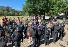 Demonstrierende und Polizisten stehen im Görlitzer Park. 