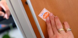 Schutzwesten für Gerichtsvollzieher – Auftrag in Kürze Eine Gerichtsvollzieherin klebt ein Pfandsiegel auf ein technisches Gerät. (Symbolbild)