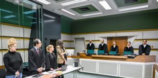 Im Gerichtssaal stehen Anwälte (l) mit der Klägerin und die Richter der 1. Kammer des Verwaltungsgerichts.