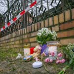 Ermittlungen zu Brand mit totem Jungen dauern an Kerzen und Blumen liegen vor einem Haus in Berlin-Mahlsdorf, in dem nach einem Feuer ein Kind gestorben ist.