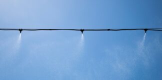 Hitzewelle: Wie gut ist das Fusion-Festival vorbereitet? Sprinkler versprühen Wasser über der Tanzfläche einer großen Festival-Bühne.