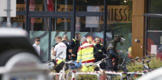 Polizei: Mutmaßlicher Geiselnehmer leicht verletzt Einsatzkräfte stehen vor einem Supermarkt neben einer verletzten Person auf einer Trage