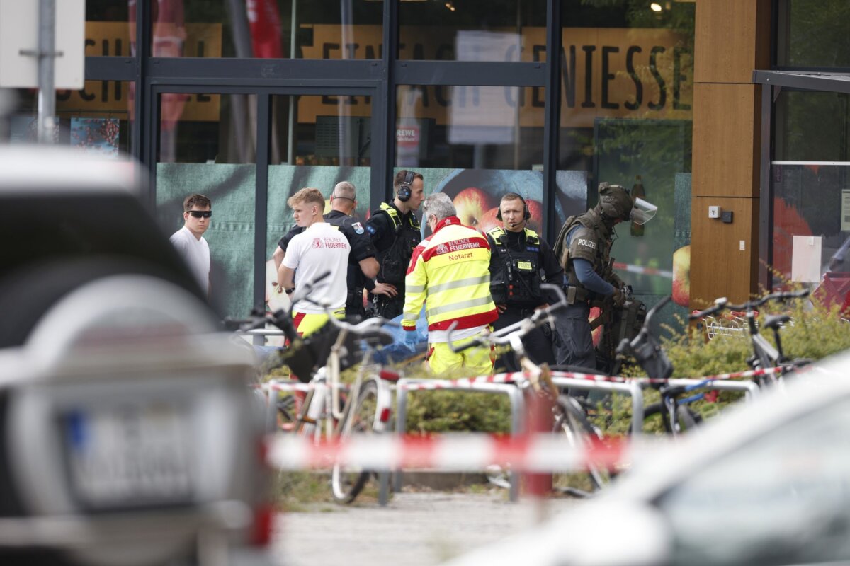 Geiselnahme in Berliner Supermarkt Einsatzkräfte stehen vor einem Supermarkt neben einer verletzten Person auf einer Trage