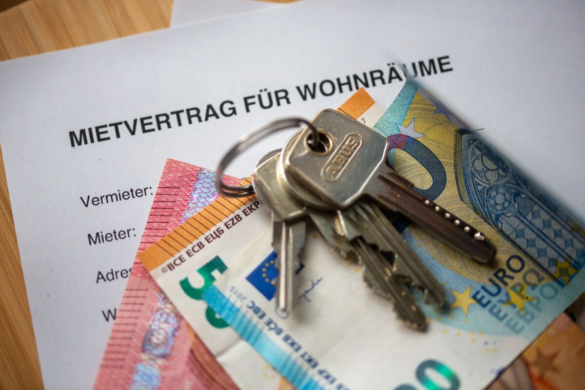 Mietvertrag, Geldscheine und Hausschlüssel auf einem Tisch Hinweise auf überhöhe Mieten lassen sich online ans Bezirksamt weitergeben. (Symbolbild)