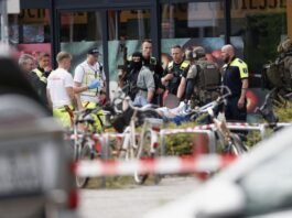 Geiselnahme in Berlin – Ermittlungen vor Abschluss Einsatzkräfte stehen nach der Geiselnahme vor dem Supermarkt in Berlin neben einer verletzten Person auf einer Trage. (Archivbild)