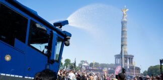 Wasserwerfer hilft schwitzenden Ravern bei Techno-Parade Ein Wasserwerfer der Polizei spendet bei der Techno-Parade «Rave The Planet» etwas Abkühlung.